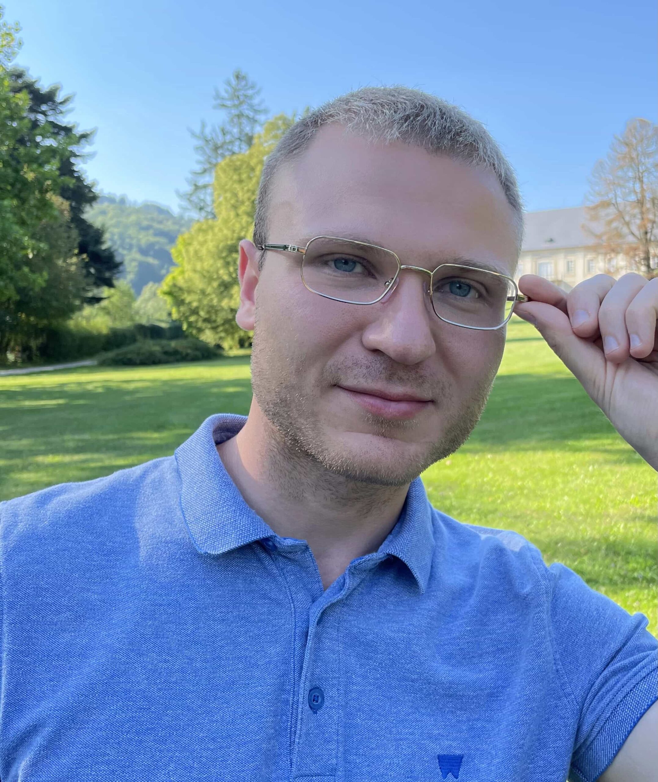 Psycholog, Coach, Szkoleniowiec, błękitna koszulka, zielone tło w parku